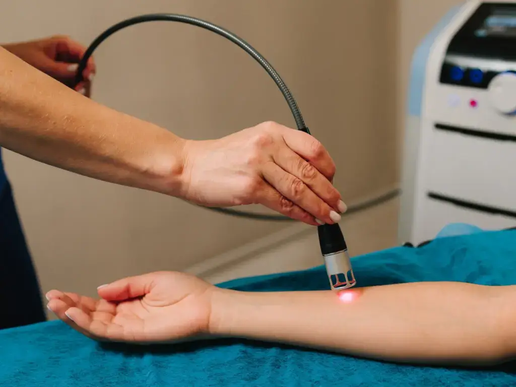 A clinician applying a cold laser handpiece to a patient soft tissue in South Tempe, AZ