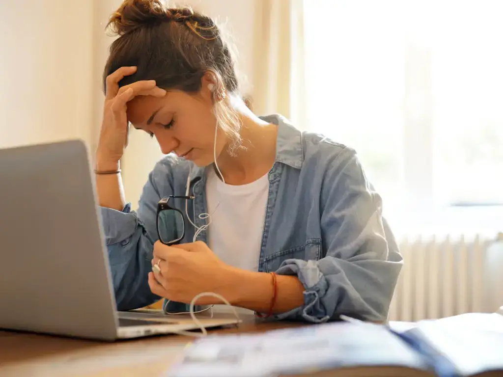 Tired woman at a laptop with fatigue and brain fog, common reasons for a health optimization visit