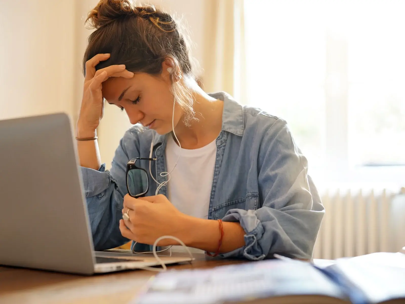 Tired woman at a laptop with fatigue and brain fog, common reasons for a health optimization visit
