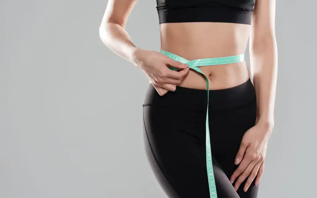 Woman measuring her waistline after non-surgical body contouring in Tempe, AZ