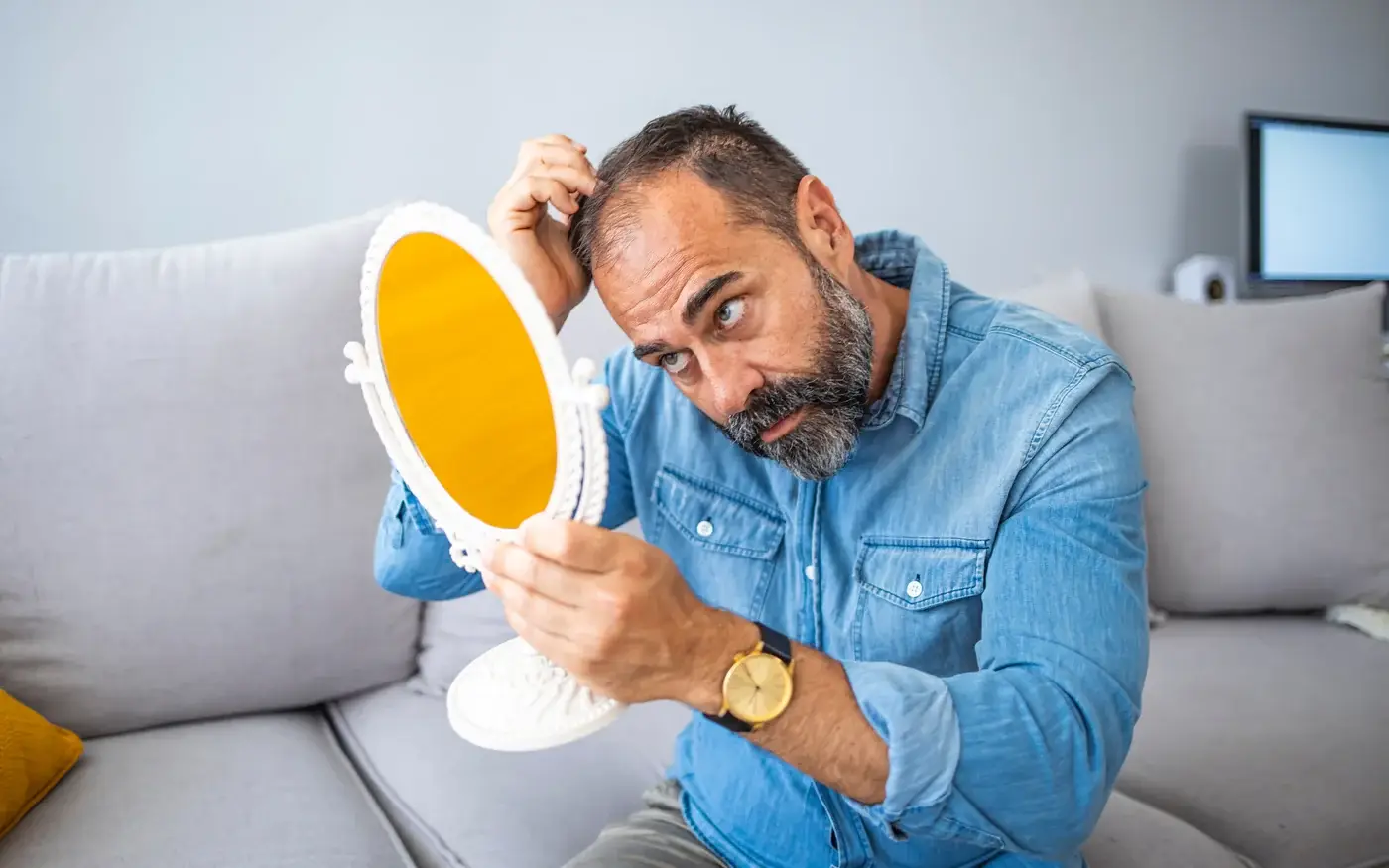 Man checking his hairline in a mirror, hair loss treatment for men in South Tempe, AZ