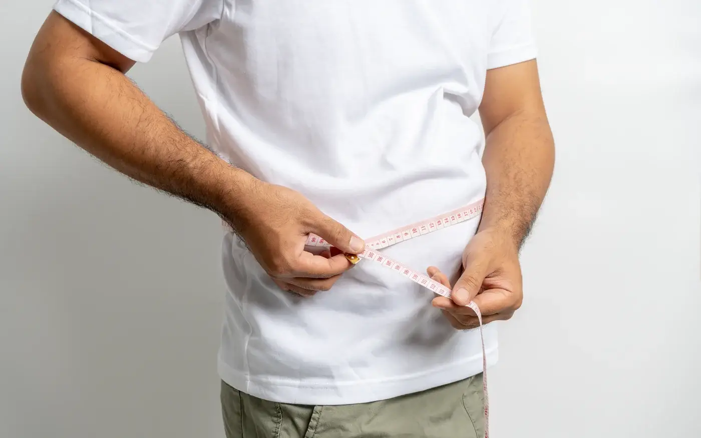 Man measuring his waistline with a tape measure, medical weight loss for men in South Tempe, AZ