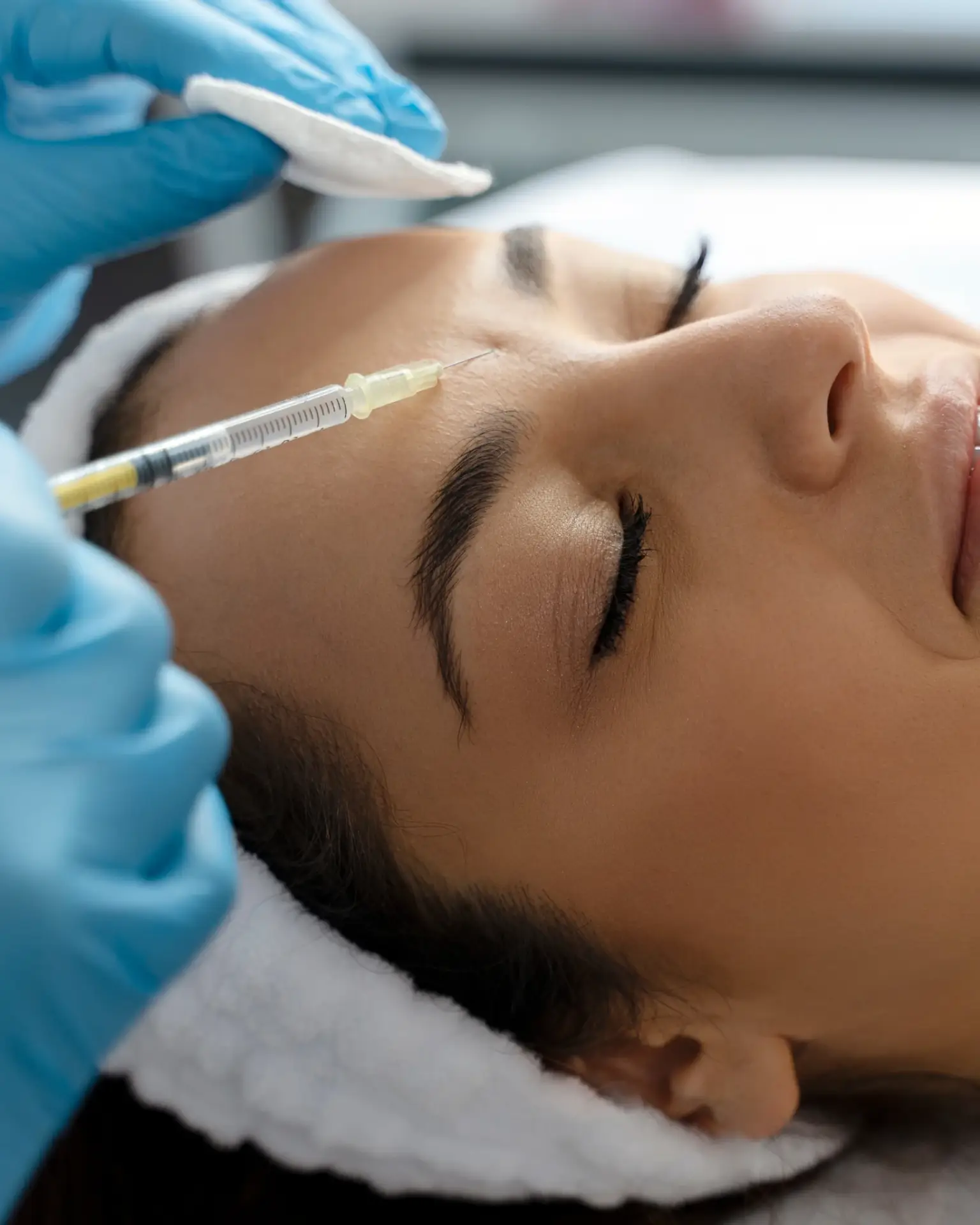 A clinician in blue gloves injecting platelet-rich plasma at the temple during a PRP facial in South Tempe, AZ