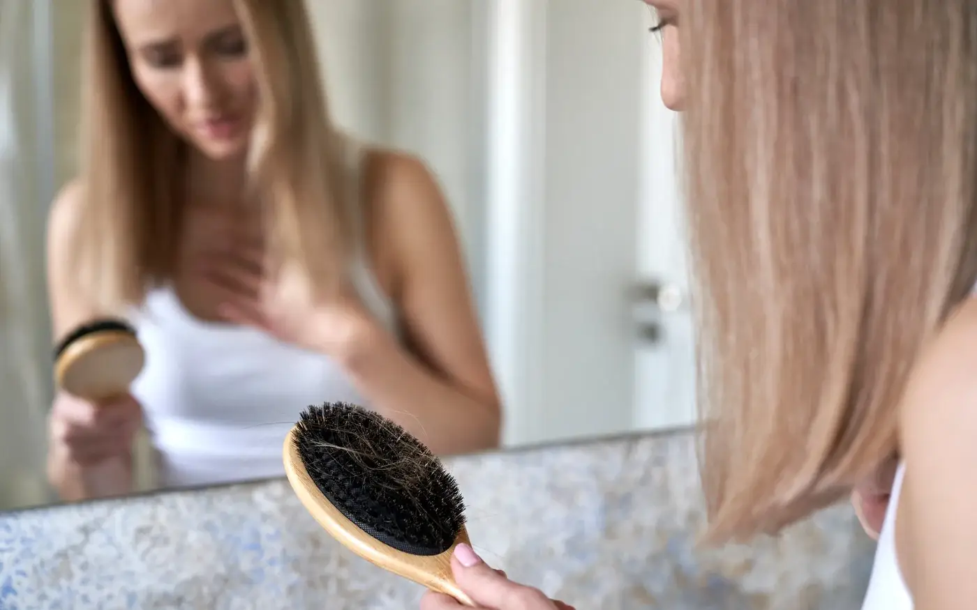 Woman looking at hair left in her hairbrush, hair loss treatment for women in South Tempe, AZ