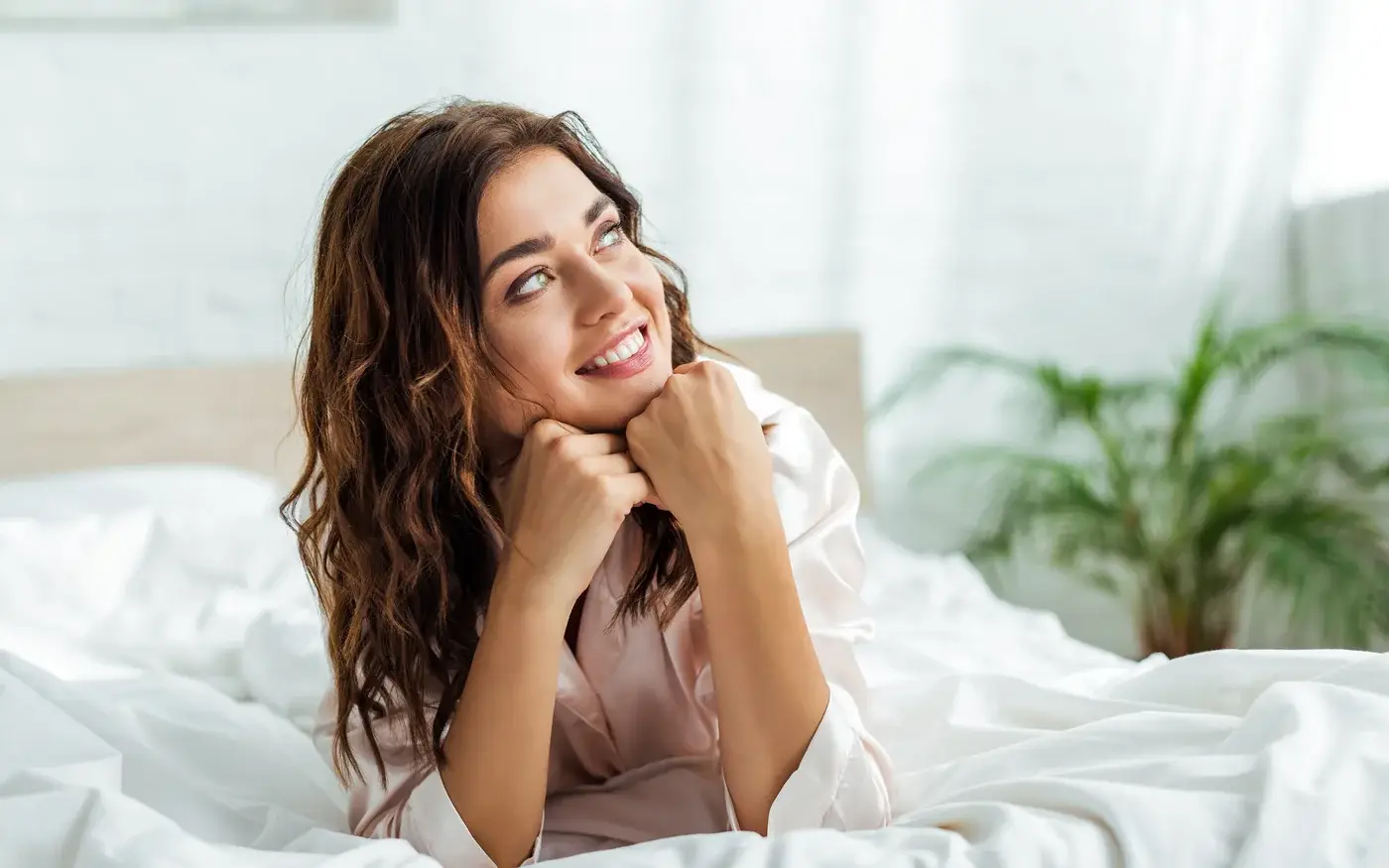 Smiling woman relaxing in bed in morning light, O-Shot sexual wellness care in South Tempe, AZ